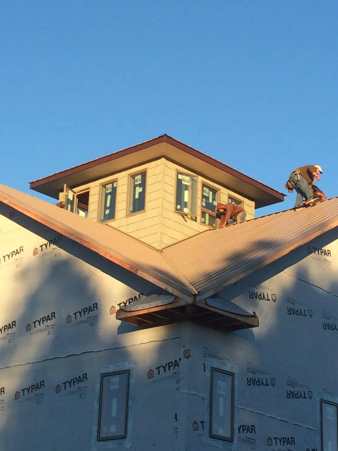 Roofers working around a rooftop cupola on a new metal roof at sunset — Roof Waterproofing in Satellite Beach by Roofing Brothers